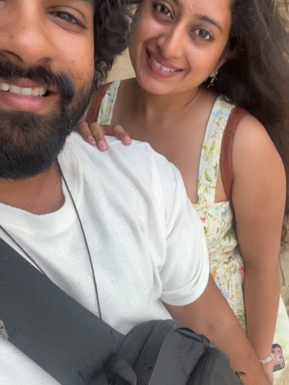 Chan and Sneha smiling in a sunny outdoor selfie