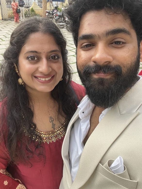 Sneha in a red outfit and Chan in a cream jacket, dressed up for a celebration